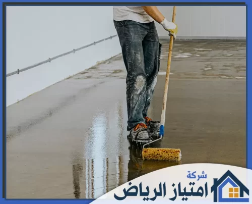 ايبوكسي كونكريت الرياض 0506986916 شركة امتياز الرياض عامل يضع طبقة إيبوكسي لامعة على أرضية خرسانية.