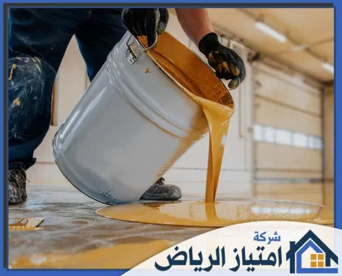 تركيب ارضيات ايبوكسي بالرياض 0506986916 شركة امتياز الرياض عامل يصب طلاء الإيبوكسي الذهبي لتغطية أرضية جراج كبيرة.