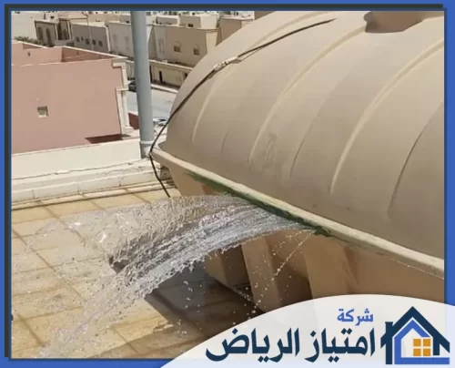 كشف تسرب خزان المياه بالرياض 0506986916 شركة امتياز الرياض خزان مياه مكسور على السطح يتسبب في هدر كميات كبيرة من المياه، مع خلفية لمبانٍ سكنية.