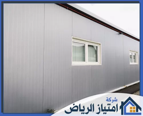 مظلات كلادينج بالرياض 0506986916 شركة امتياز الرياض مبنى صناعي حديث بكسوة معدنية رمادية ونوافذ بيضاء، يجمع بين البساطة والعملية في التصميم المعماري المعاصر.