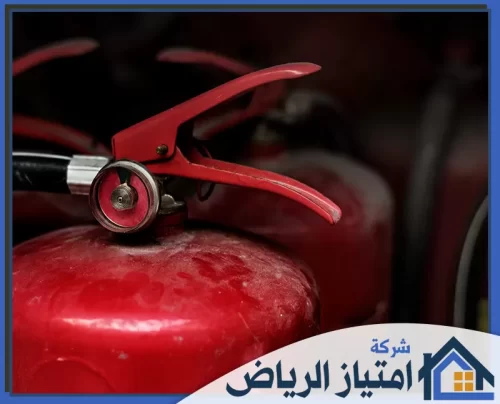 جهاز كشف تسربات خطوط الحريق بالرياض 0506986916 شركة امتياز الرياض لقطة قريبة لمقبض وعداد طفاية حريق حمراء، تبرز أهمية معدات السلامة والوقاية في حالات الطوارئ بوضوح عالٍ.